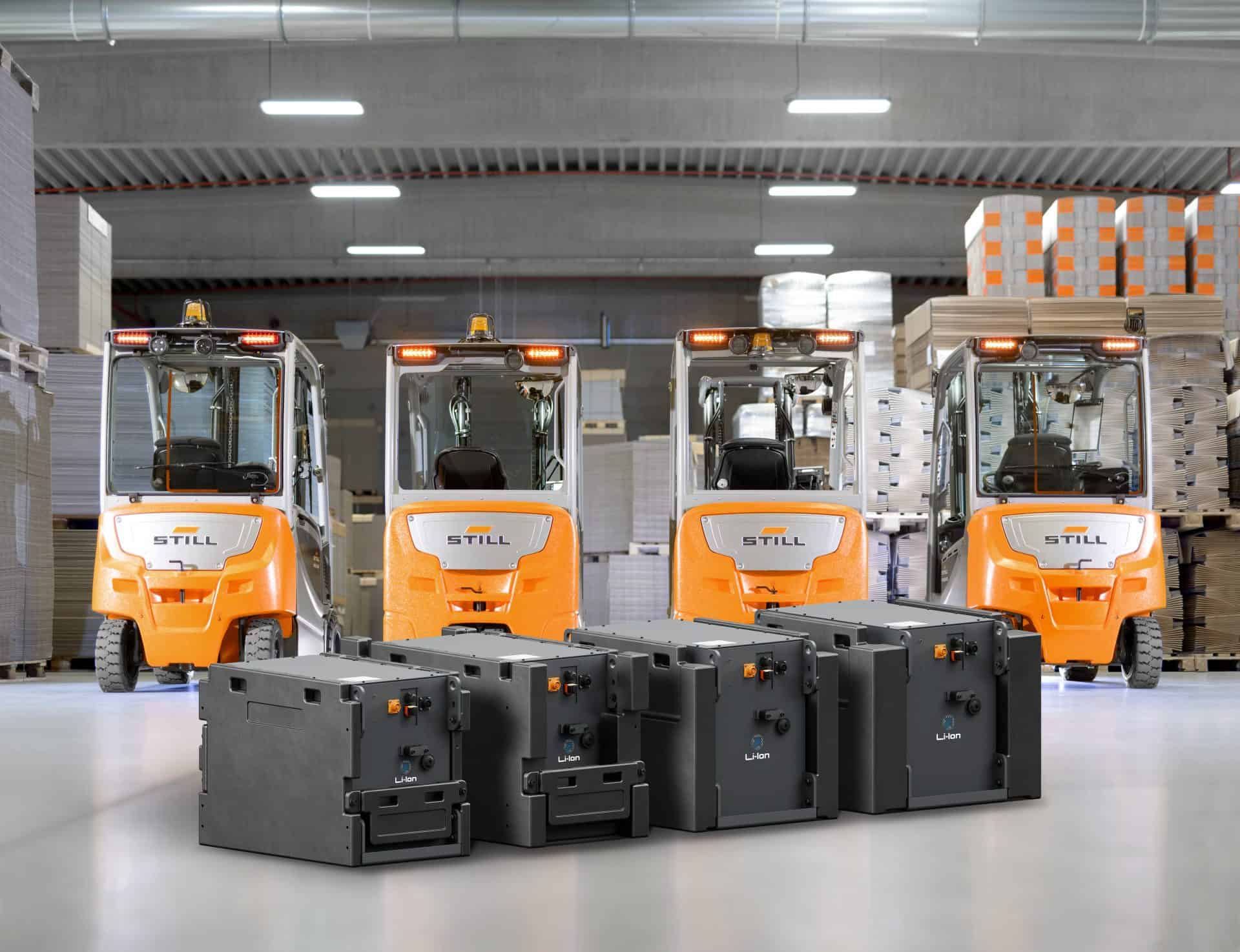 Vier elektrische Gabelstapler im Lager mit Batterien im Vordergrund.