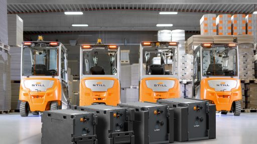 Vier elektrische Gabelstapler im Lager mit Batterien im Vordergrund.