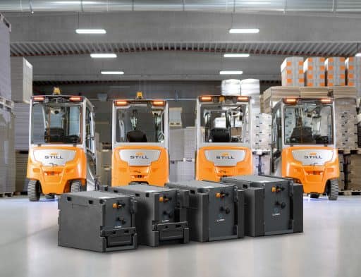 Vier elektrische Gabelstapler im Lager mit Batterien im Vordergrund.