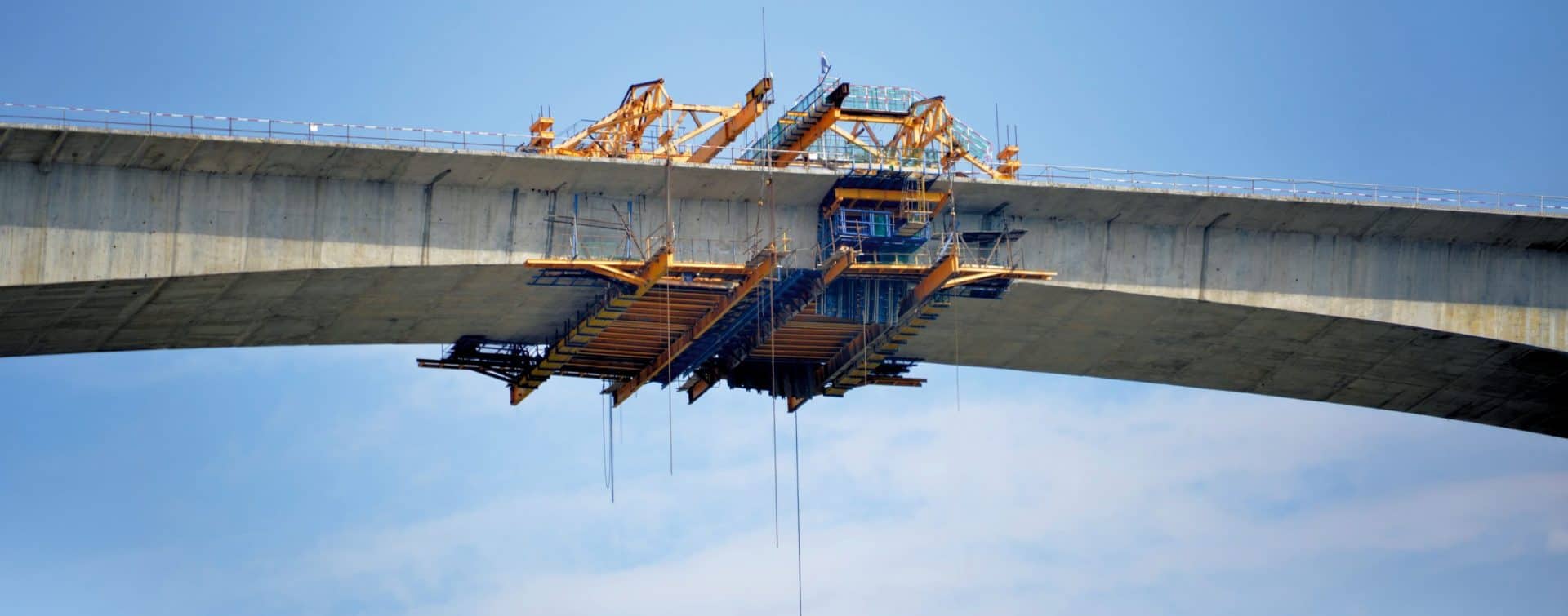 Kran und Baugerüst beim Bau einer Brücke gegen blauen Himmel.