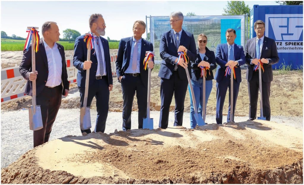 Geschäftsleute bei Baustart mit Schaufeln und Ribbons.