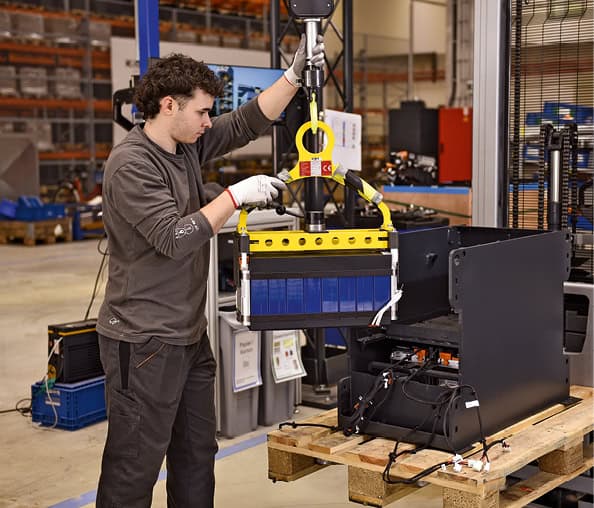 Mann arbeitet mit Roboter in einer Fabrikhalle bei der Montage.